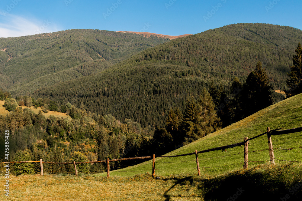 Einfacher hölzerner Zaun an einer Weide vor der bergigen Landschaft der Steiermark Einfacher hölzerner Zaun an einer Weide vor der bergigen Landschaft der Steiermark