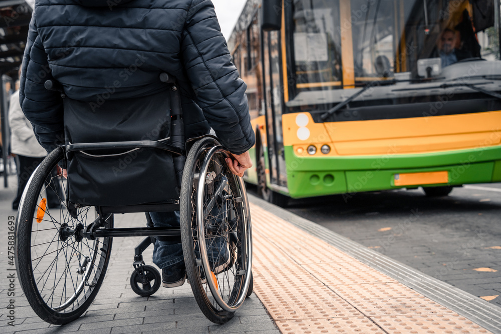 Fototapeta premium Person with a physical disability waiting for city transport with an accessible ramp.