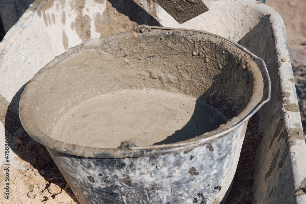 A basket filled with sand and dry cement mixture stands on the path