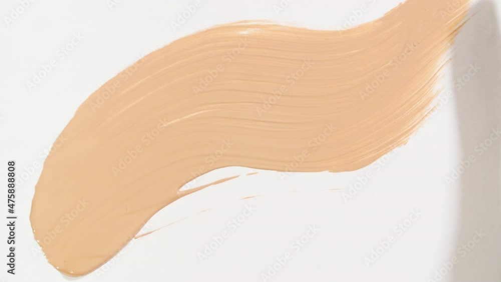 Macro shot and slow motion of a brush, applicator, smear, concealer isolated on white background. Advertising professional cosmetics. Closeup of a cosmetic liquid foundation or cream beige color. 4k Macro shot and slow motion of a brush, applicator, smear, concealer isolated on white background. Advertising professional cosmetics. Closeup of a cosmetic liquid foundation or cream beige color. 4k