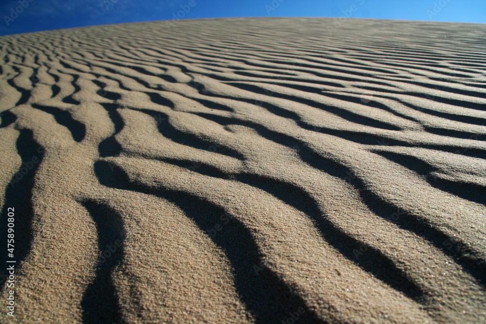 Beautiful dune sand textures as wind blows the sand across with a beautiful blue sky Beautiful dune sand textures as wind blows the sand across with a beautiful blue sky