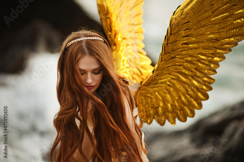 Young beautiful woman fallen angel stands on sea beach enjoy nature. costume bird white wings.