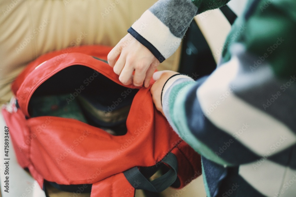 Dziecko pakujące plecak przed wyjściem do szkoły - obrazy, fototapety, plakaty 