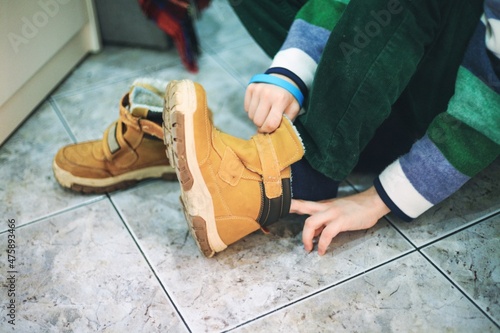 Dziecko przygotowujące się do wyjścia z domu i zakładające buty photo