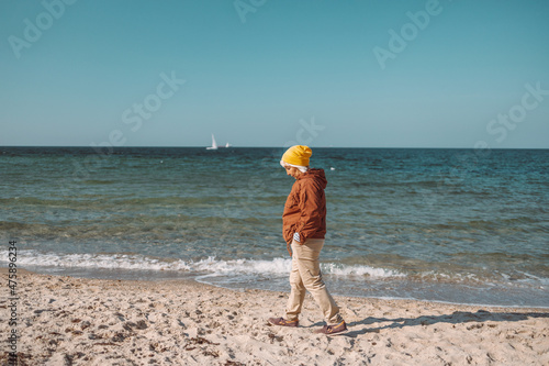 Attractive middle-aged woman enjoys looking at water while walking on the beach near the sea