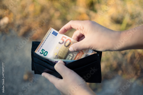 Female holding wallet with euro money. Unemployment, poverty on color background photo