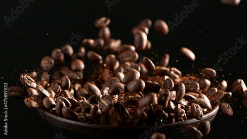 Freeze motion of flying roasted coffee beans on black.