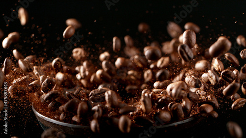 Freeze motion of flying roasted coffee beans on black.