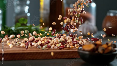 Foto Freeze motion of falling legume mix on cutting board.