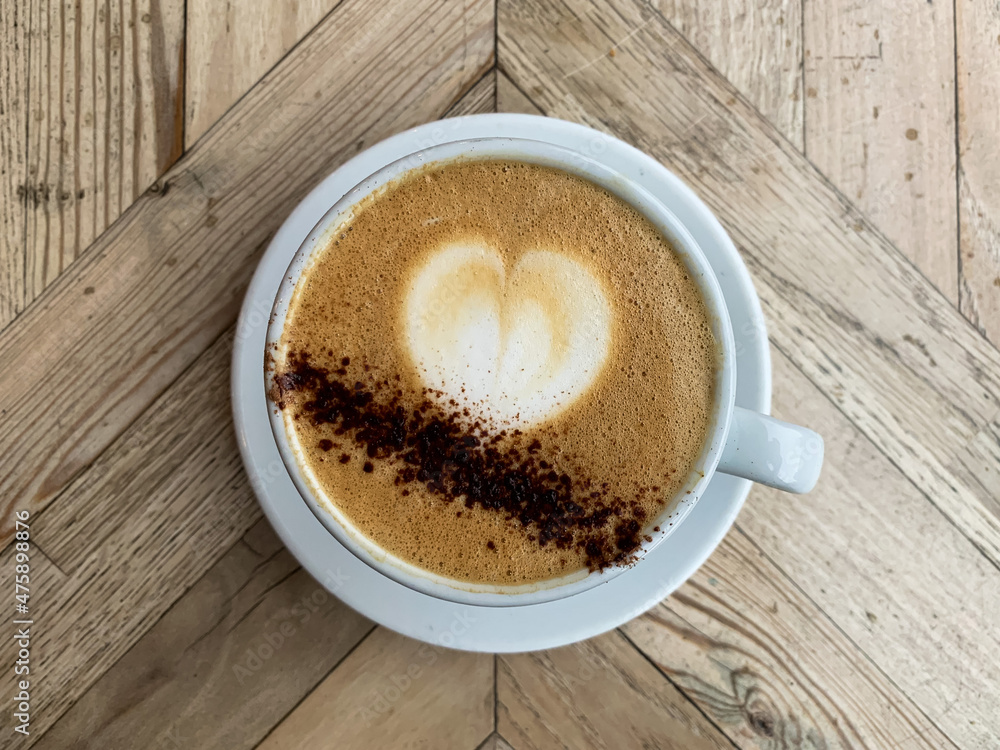 A mug of flat white coffee on a wooden background. Coffee art. Heart shape latte art Coffee in white cup A mug of flat white coffee on a wooden background. Coffee art. Heart shape latte art Coffee in white cup