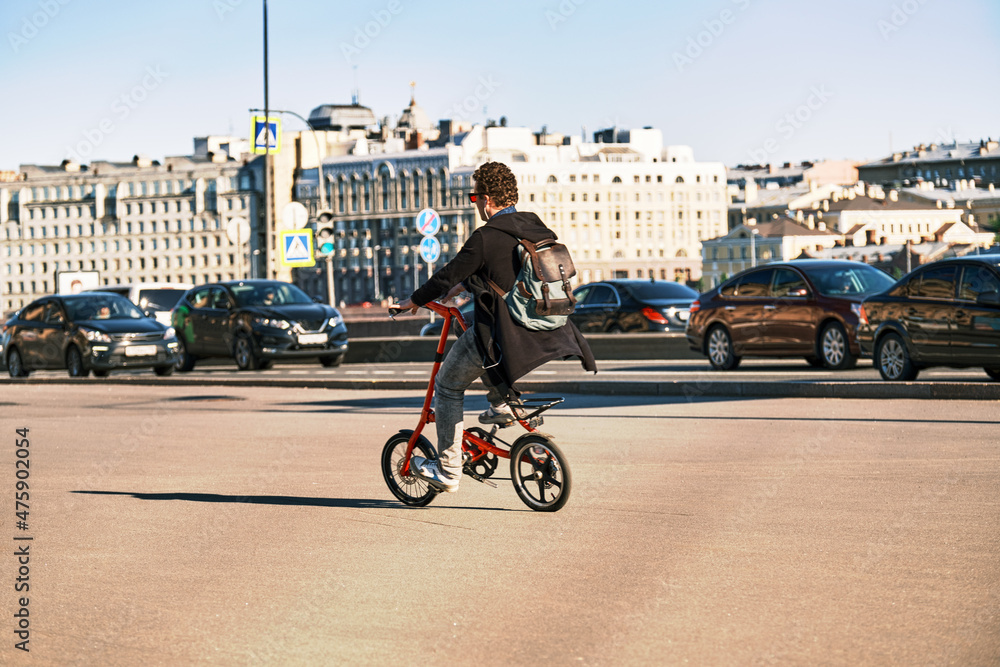 Obraz premium A man rides a bicycle through the city. A cyclist rides a bike among cars