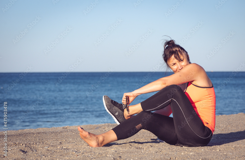 Active woman putting on a sneaker to start running, sports exerc