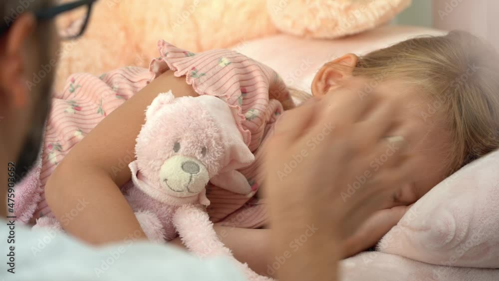 Back view of father touches forehead of sick little girl and measure temperature with thermometer. Child lies in bed with fever and coughs. Treatment for illness, flu and cold Back view of father touches forehead of sick little girl and measure temperature with thermometer. Child lies in bed with fever and coughs. Treatment for illness, flu and cold