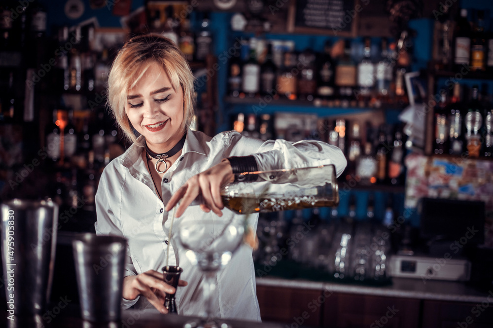 Girl barman formulates a cocktail at the beerhouse
