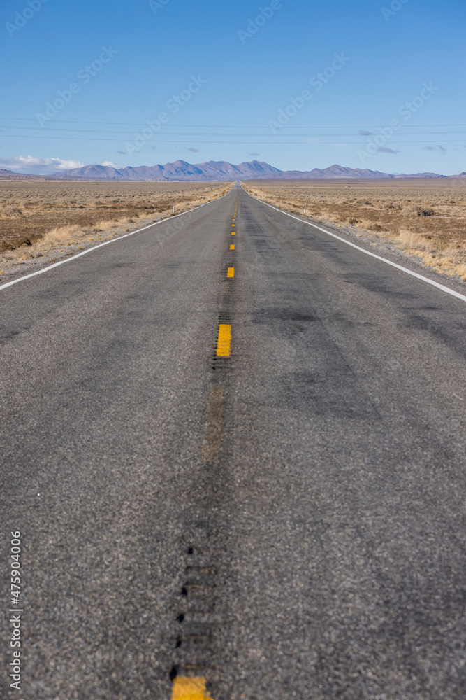 Lonely asphalt road stretches into the middle of nowhere in the desert