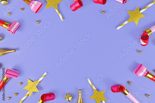Party frame with blowouts, champagne bottles, drinking straws and bells on violet background with copy space