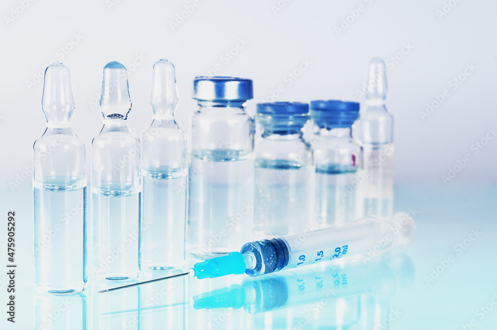 syringe and diferent kind of ampoules and vials close-up on white background with reflection syringe and diferent kind of ampoules and vials close-up on white background with reflection