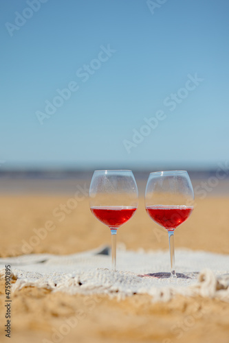 two glasses of red wine or juice at a picnic on the shore of a lake or ocean. a romantic date between two people in love. a basket with delicious food for a picnic and an outdoor dinner. beautiful