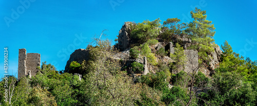 ruins of fortress walls on wooded mountain slopes in the antique city of Olympos, Turkey photo