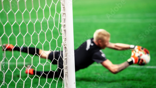 Obraz na płótnie The soccer goalkeeper saves the goal from a penalty kick while jumping. Selective focus on the boom. w salonie