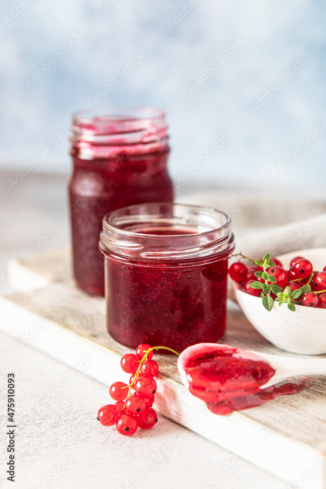 Homemade red currant jam or jelly in glass jars and red currants fresh berries on wooden cutting board. Homemade red currant jam or jelly in glass jars and red currants fresh berries on wooden cutting board.