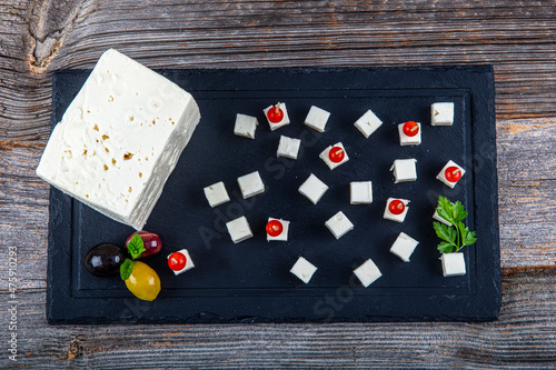 Feta Cheese Cubes on wooden cutting board. Square cubes of feta cheese isolated on wood board with knife.