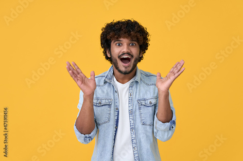 Canvas Amazed excited young indian man looking at camera with wow face expression feeling surprised advertising shopping promotion, unbelievable betting win standing isolated on yellow background