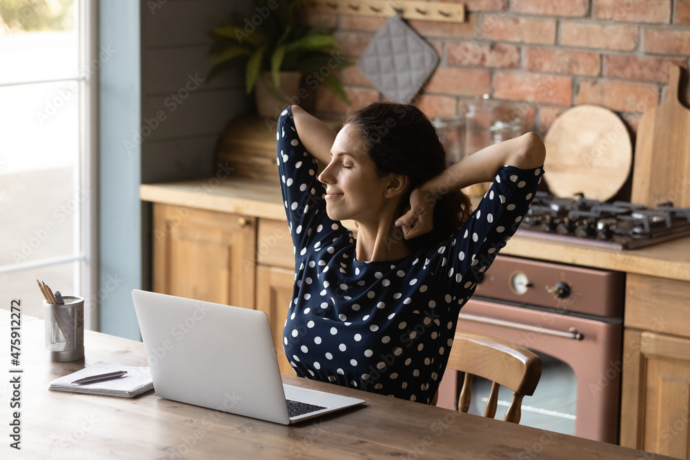 Happy beautiful millennial generation latin woman stretching back, relaxing after finishing working on computer in old-fashioned kitchen, meeting deadlines, enjoying break pause pastime alone indoors. Happy beautiful millennial generation latin woman stretching back, relaxing after finishing working on computer in old-fashioned kitchen, meeting deadlines, enjoying break pause pastime alone indoors.
