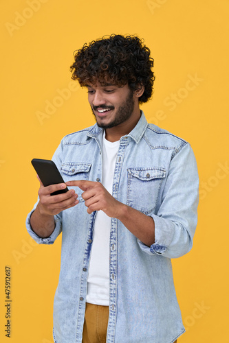 Papier peint Happy indian young man using cell phone isolated on yellow background
