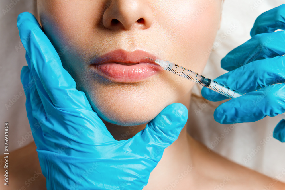 A woman makes lip shape correction in a cosmetology clinic. Lips injections, lip augmentation.