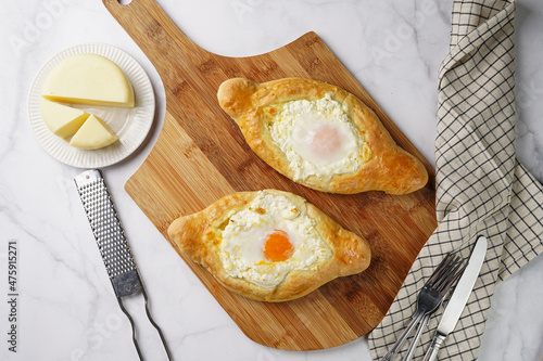 Traditional georgian dish of cheese-filled bread adjarian khachapuri with fried egg on a wooden board photo