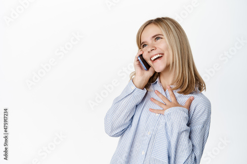 Cute little girl, beautiful blond kid talking on mobile phone, having conversation on smartphone, answer a call, standing over white background
