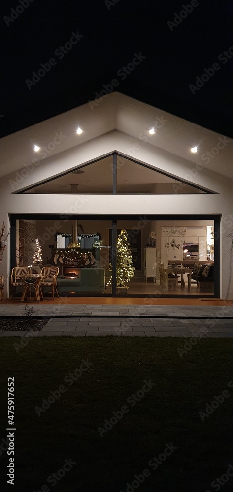 Fototapeta premium Dom parterowy w ogrodzie, oświetlenie elewacji, duże okna w domu