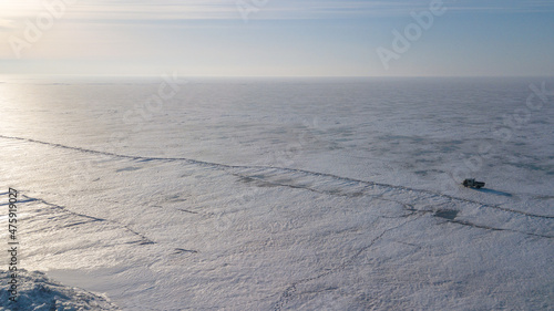 Lake Khanka in the Primorsky Territory in winter. View from above. Frozen coast of a large lake. Arctic landscape. A Russian minibus travels along a frozen lake. photo