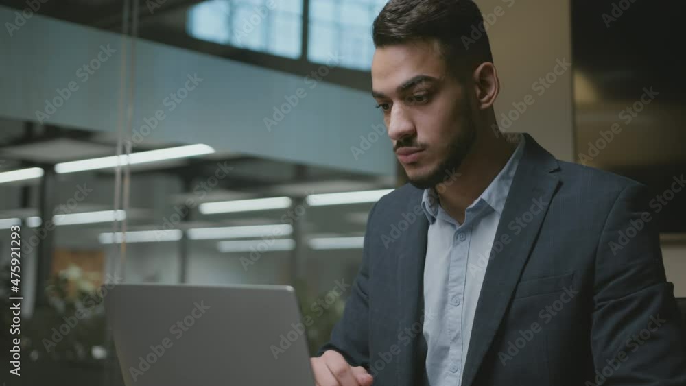 Working process. Young middle eastern man manager typing on laptop, making online plan and financial report at office Working process. Young middle eastern man manager typing on laptop, making online plan and financial report at office