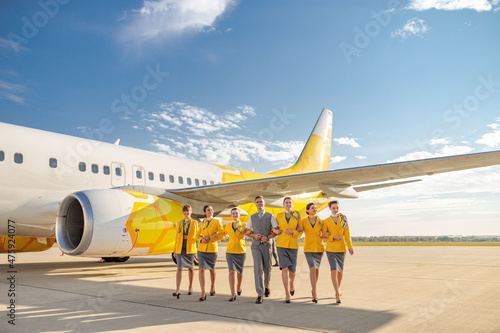 Принти на полотні Cheerful aircrew walking down airfield under blue sky