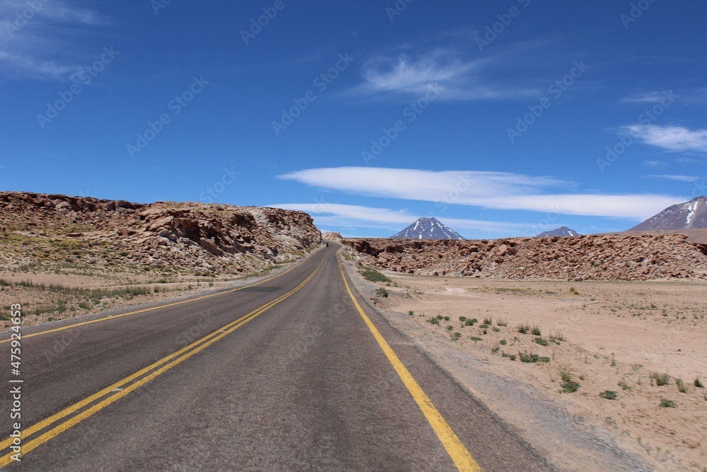Road (Route 23) on the Atacama Desert with volcanos on the background, Chile, South America.