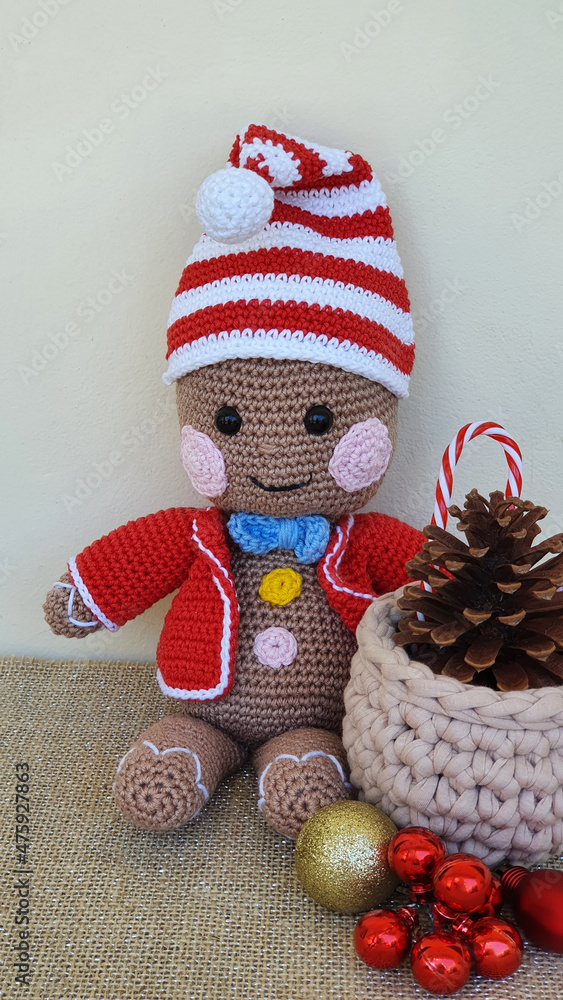 Fototapeta premium Cute handmade toy, colorful crocheted doll and Christmas ornaments on the table.