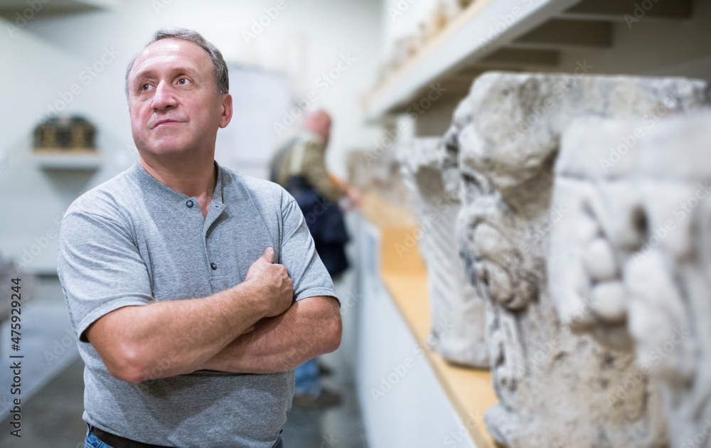 Obraz premium portrait of adult man is visiting museum and looking at the exposition indoor.