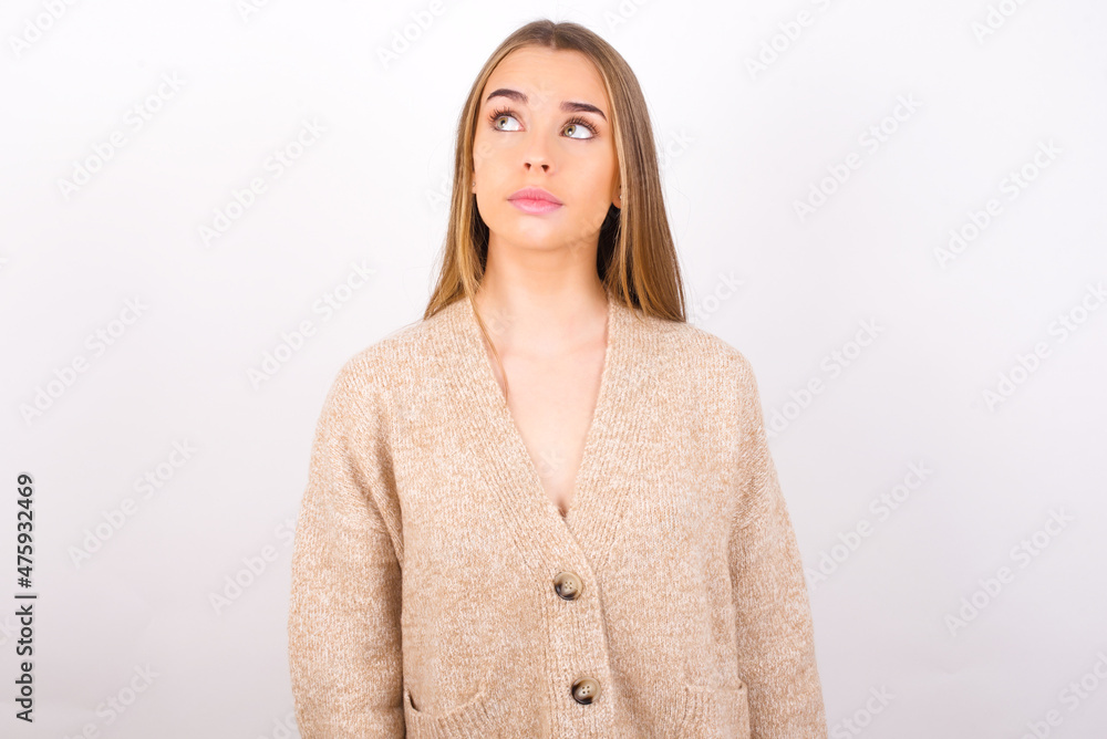 young caucasian girl wearing knitted sweater over white background looking aside into empty space thoughtful young caucasian girl wearing knitted sweater over white background looking aside into empty space thoughtful