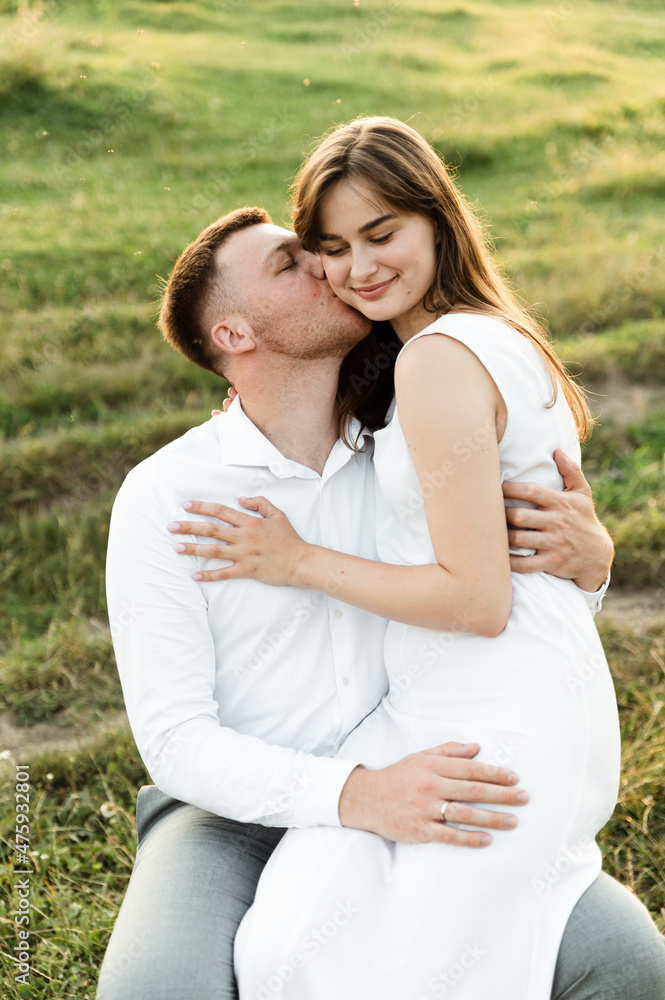 the newlyweds are sitting on a chair and hugging tenderly. girl with a boyfriend on a romantic date at sunset of the day. beautiful couple in the field. the newlyweds are sitting on a chair and hugging tenderly. girl with a boyfriend on a romantic date at sunset of the day. beautiful couple in the field.