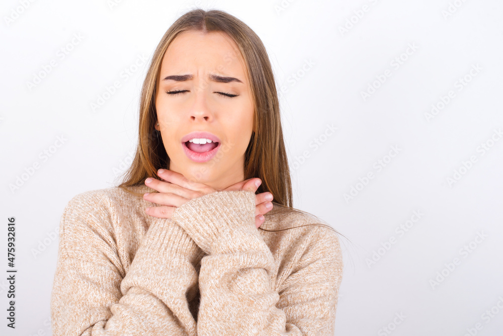 young caucasian girl wearing knitted sweater over white background shouting suffocate because painful strangle. Health problem. Asphyxiate and suicide concept. young caucasian girl wearing knitted sweater over white background shouting suffocate because painful strangle. Health problem. Asphyxiate and suicide concept.