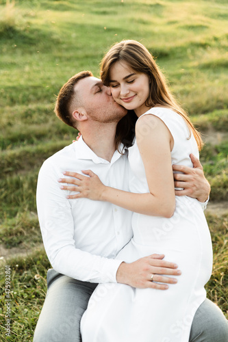 the newlyweds are sitting on a chair and hugging tenderly. girl with a boyfriend on a romantic date at sunset of the day. beautiful couple in the field.
