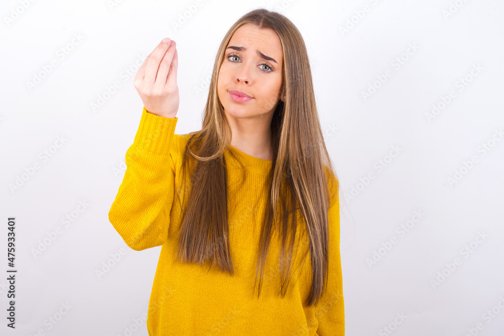 Young caucasian girl wearing yellow sweater over white background Doing Italian gesture with hand and fingers confident expression Young caucasian girl wearing yellow sweater over white background Doing Italian gesture with hand and fingers confident expression