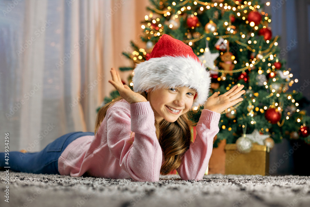 A cute girl lies by the Christmas tree and dreams. Dreams Come True. Children waiting for the new year and christmas A cute girl lies by the Christmas tree and dreams. Dreams Come True. Children waiting for the new year and christmas