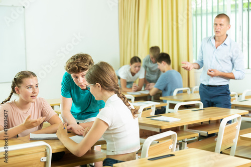 Young students sitting in classroom in groups and performing group tasks.