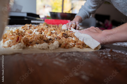 Rolling apple filled pastry dough into a strudel