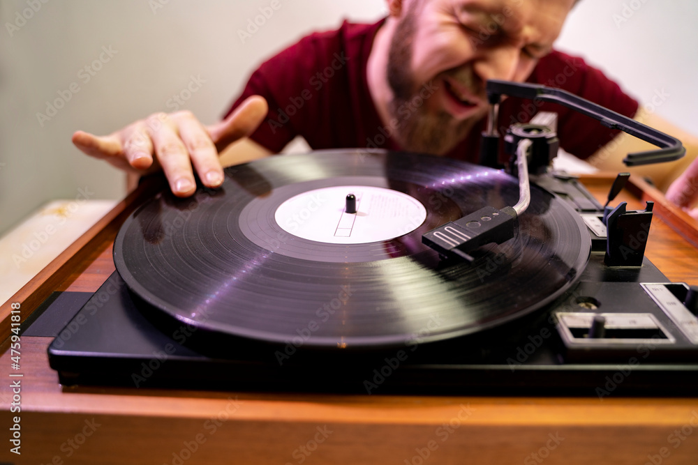 Funny closeup shot, hipster bearded man scratching vinyl record on vintage turntable 