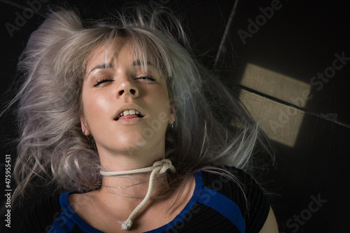 Foto Crime scene simulation: dead girl with hands tied lying on the floor