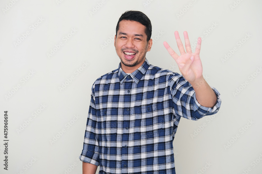Adult Asian man smiling happy while showing four fingers sign Adult Asian man smiling happy while showing four fingers sign